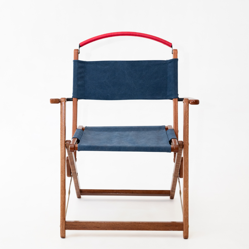 Director's chair with blue canvas seat and backrest and red handle on a white background